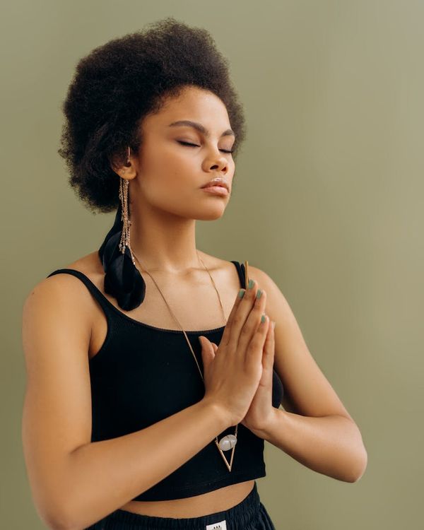 Woman in a serene yoga pose, embodying harmony and balance in a dark studio.